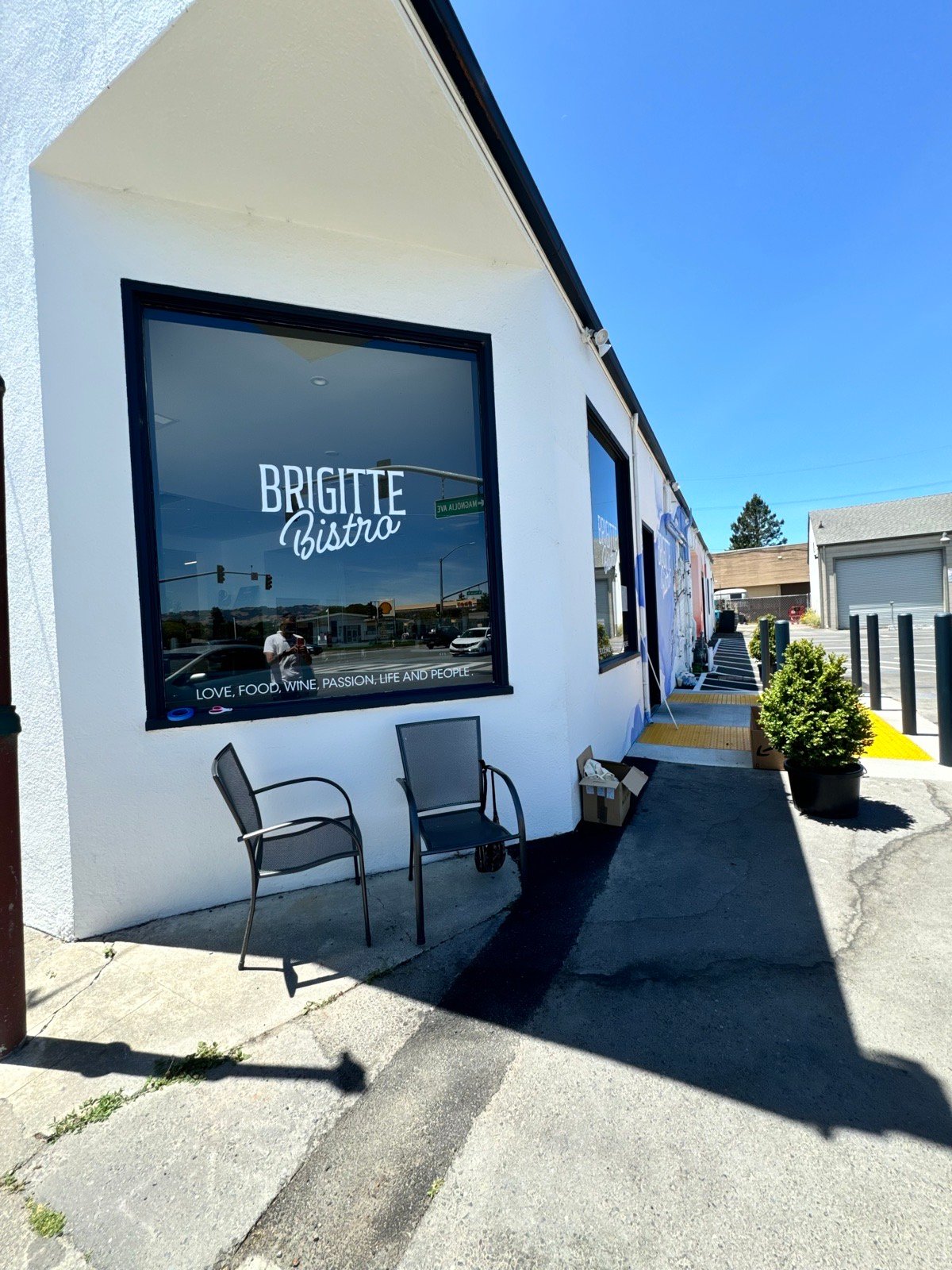 The corner window with the Brigitte Bistro decal and two chairs out front