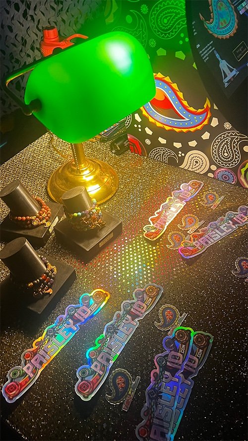 Holographic Paisley ID stickers and bracelets under a green lamp